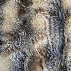 May include: Close-up of a soft, plush fabric with a striped pattern in shades of gray and brown. The fabric has a fuzzy texture and appears to be made of faux fur.