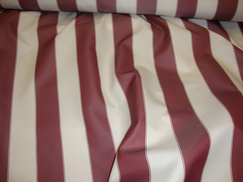 May include: Red and white striped fabric with a subtle sheen. The fabric is folded and draped, showing the texture and pattern.