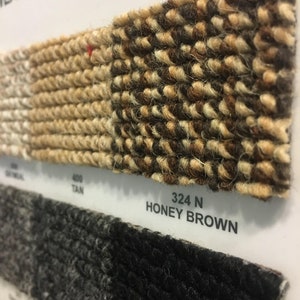 May include: Close-up of carpet samples in tan, brown, and black. The sample labeled "324 N HONEY BROWN" is a brown and tan carpet with a woven texture.