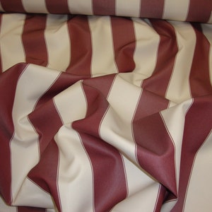 May include: Red and cream striped fabric with a woven texture. The fabric is folded and draped, showing the stripes.
