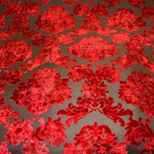 Pode incluir: Tecido de veludo vermelho com um padr&atilde;o de damasco. O tecido tem um design em relevo texturizado.