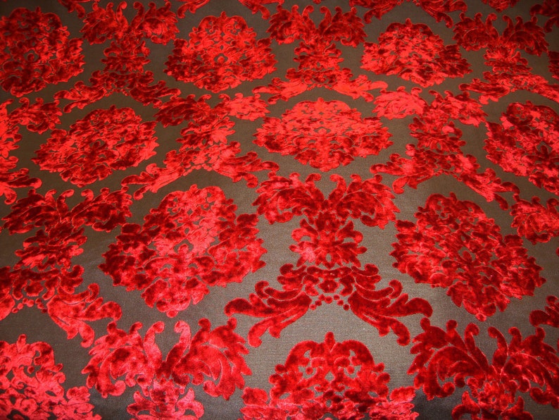 Pode incluir: Tecido de veludo vermelho com um padr&atilde;o de damasco. O tecido tem um design em relevo texturizado.