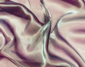 May include: A close-up of iridescent pink and white sheer fabric with a smooth, silky texture. The fabric is draped and folded, creating a soft and flowing look.