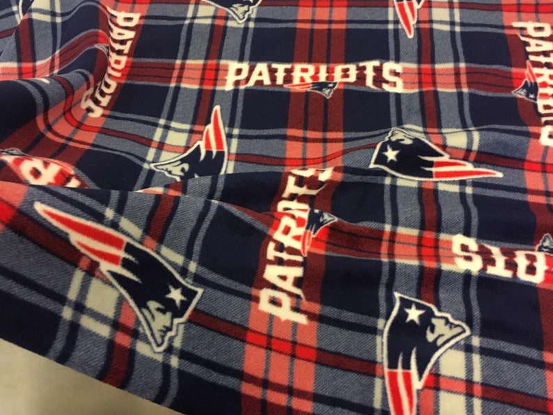 May include: Red, white, and blue plaid fabric with a repeated pattern of the New England Patriots logo and the word "Patriots".