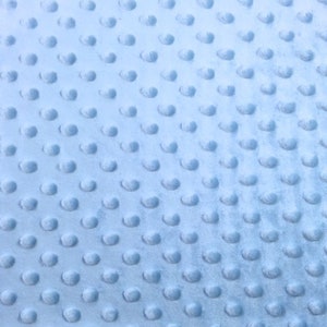May include: A light blue fabric with a textured pattern of small raised dots. The fabric has a soft, plush feel.