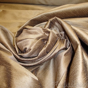 May include: A close-up of a brown silk fabric with a subtle sheen. The fabric is draped and folded, creating a soft, luxurious texture.