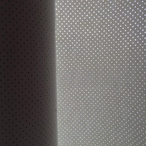 K&ouml;nnte beinhalten: Eine Rolle aus wei&szlig;em Material mit einem gleichm&auml;&szlig;igen Muster aus kleinen, regelm&auml;&szlig;ig angeordneten kreisf&ouml;rmigen Perforationen. Die Oberfl&auml;che weist eine feine Textur auf und ist teilweise beleuchtet, was einen Verlauf von Schatten zu Licht erzeugt.
