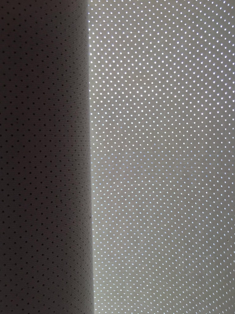 K&ouml;nnte beinhalten: Eine Rolle aus wei&szlig;em Material mit einem gleichm&auml;&szlig;igen Muster aus kleinen, regelm&auml;&szlig;ig angeordneten kreisf&ouml;rmigen Perforationen. Die Oberfl&auml;che weist eine feine Textur auf und ist teilweise beleuchtet, was einen Verlauf von Schatten zu Licht erzeugt.