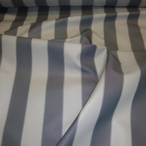 May include: A fabric with alternating stripes of white and gray. The fabric is folded and draped, showing the texture of the material.