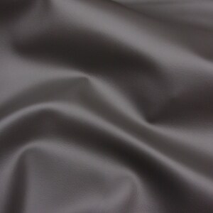 May include: A close-up of a smooth, grey fabric with a subtle texture. The fabric is draped and folded, creating soft curves and folds.