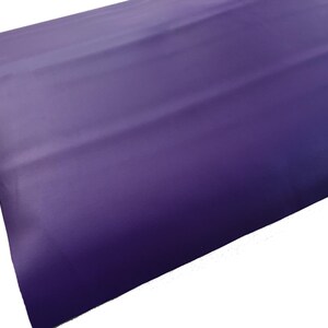 May include: A close-up of a smooth, purple fabric with a slight sheen. The fabric is folded in thirds, creating a subtle texture.