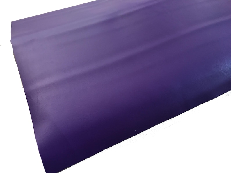 May include: A close-up of a smooth, purple fabric with a slight sheen. The fabric is folded in thirds, creating a subtle texture.