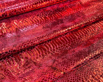 May include: Red fabric with a snakeskin pattern. The fabric is shiny and has a metallic sheen.