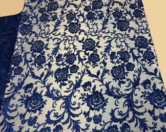 May include: Blue floral lace fabric with a delicate pattern of flowers and vines. The lace is sheer and has a soft, flowing texture.