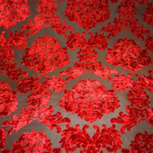 Pode incluir: Tecido de veludo vermelho com um padr&atilde;o de damasco. O tecido tem um design em relevo texturizado.