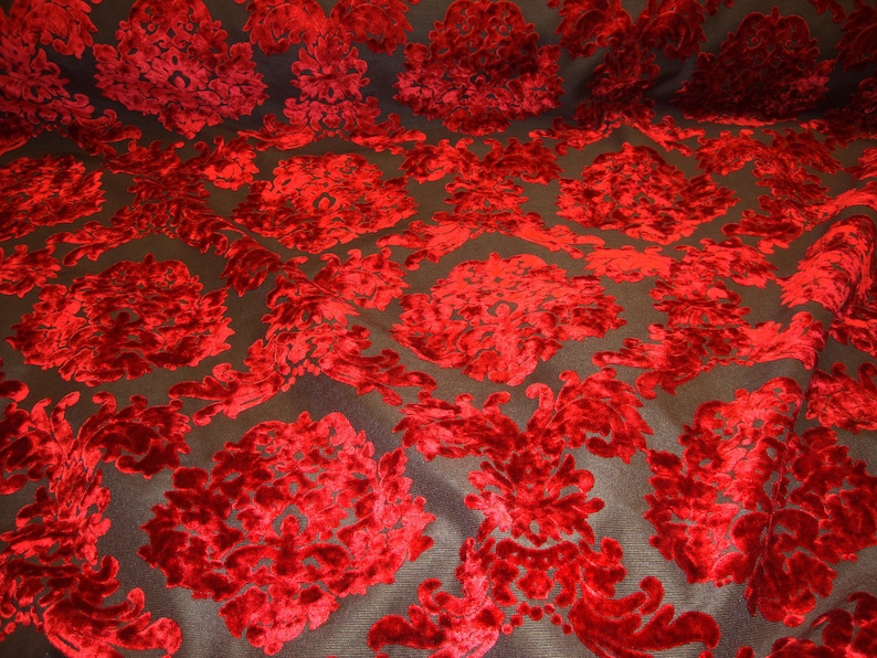 Pode incluir: Tecido de veludo vermelho com um padr&atilde;o de damasco sobre um fundo preto.