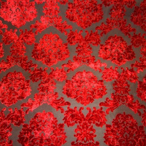 Pode incluir: Tecido de veludo vermelho com um padr&atilde;o de damasco. O tecido tem um design em relevo texturizado.