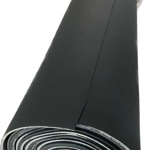 May include: A rolled-up, black sheet of material, possibly rubber or a similar flexible substance. The roll is tightly wound, revealing layers of the material with a silver-colored edge. The top is covered in clear plastic.