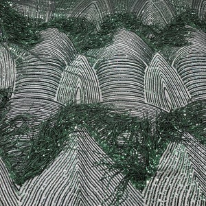 May include: Green sequined fabric with fringe detailing. The sequins are arranged in a geometric pattern, creating a modern and stylish look.