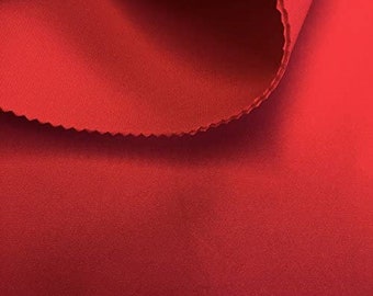 May include: Close-up of a smooth, red fabric with a slight sheen. The fabric is folded over, showing the underside.