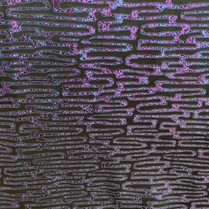 May include: Close-up of a dark fabric with a repeating pattern of shimmering, iridescent lines in shades of purple and blue. The lines create a maze-like design against a dark background, giving a textured appearance. The fabric has a subtle sheen.