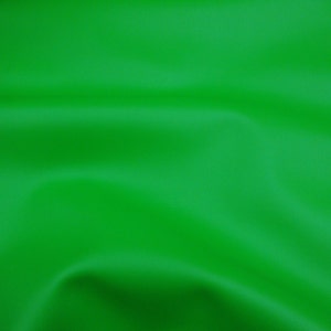 May include: A solid, vibrant green fabric with a smooth, matte texture. The material is draped in soft, flowing folds that create subtle shadows and highlights across the surface, emphasizing the consistent, bright green color throughout.