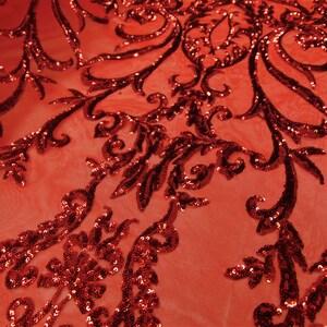 May include: Red sequined fabric with a floral pattern. The sequins are small and closely spaced, creating a shimmering effect. The fabric is sheer and lightweight.