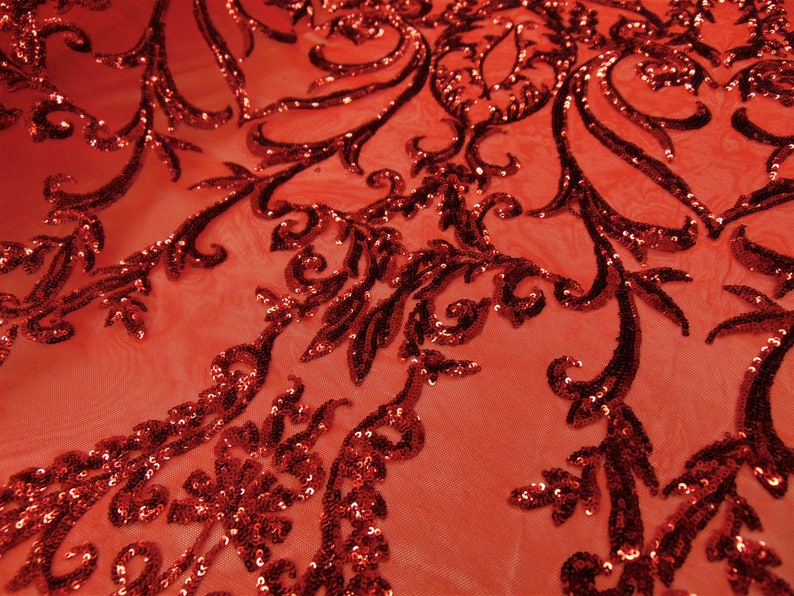 May include: Red sequined fabric with a floral pattern. The sequins are small and closely spaced, creating a shimmering effect. The fabric is sheer and lightweight.
