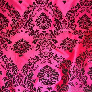 May include: A pink fabric with a black damask pattern. The fabric has a shiny, satin-like finish.