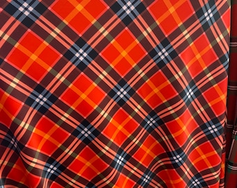 May include: Red, orange, black, and white plaid fabric with a diagonal pattern.