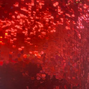 May include: Red sequin fabric with a shiny finish. The sequins are arranged in a circular pattern.