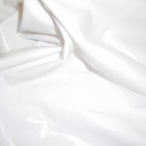 Peut inclure: Un tissu blanc uni avec une surface lisse, brillante et r&eacute;fl&eacute;chissante. Le mat&eacute;riau est drap&eacute; en plis doux et fluides, cr&eacute;ant des reflets et des ombres qui soulignent sa texture brillante semblable &agrave; du vinyle et sa couleur blanche uniforme.