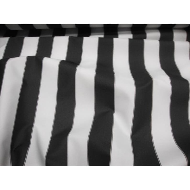 May include: Close-up of a fabric with a bold black and white striped pattern. The stripes are vertical and evenly spaced, creating a classic and graphic design. The fabric appears to be smooth and possibly a medium weight.