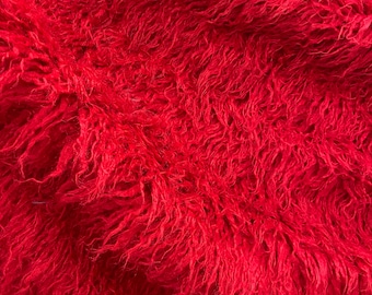 May include: Red fluffy fabric with a soft, plush texture. The fabric is made of long, thin fibers that are tightly woven together.