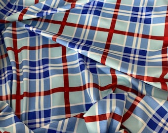 May include: Blue and red plaid fabric with a white background. The fabric is folded and wrinkled.