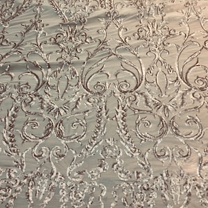 May include: Silver sequined fabric with a floral pattern on a white mesh background.
