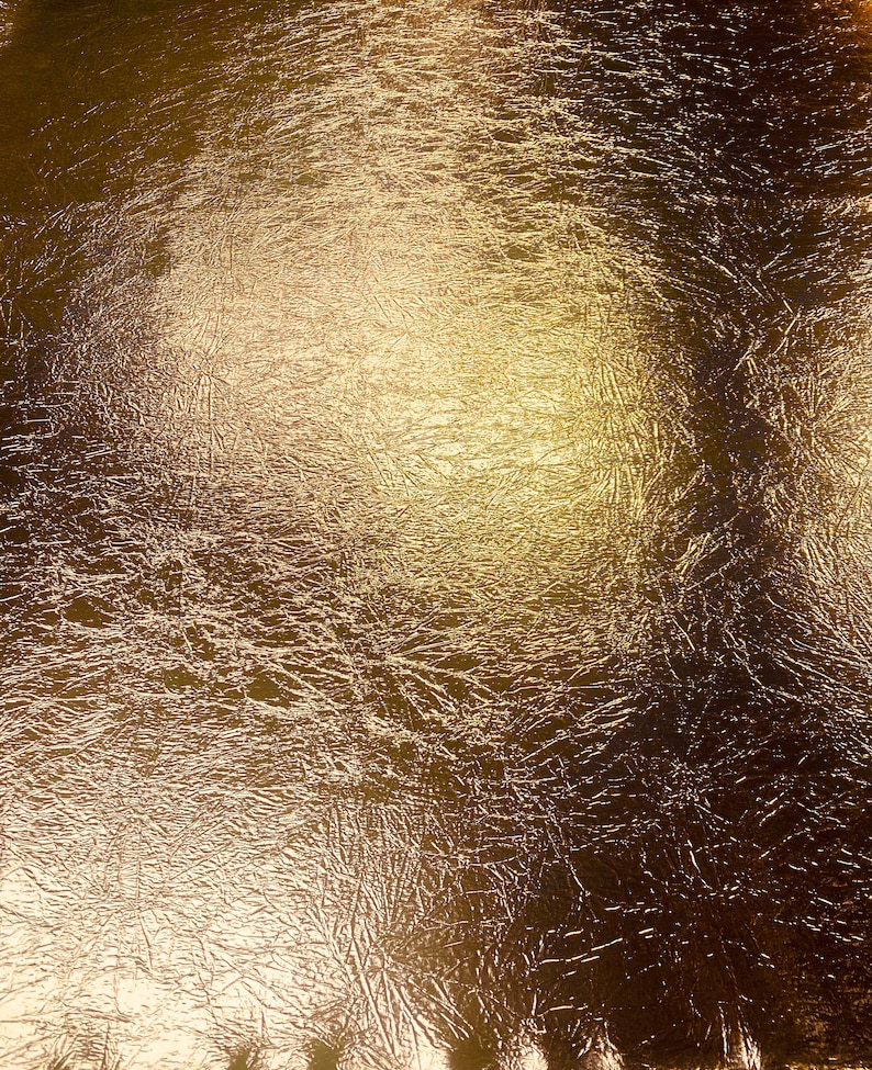 May include: A textured gold metallic surface with a subtle sheen. The surface has a wrinkled, crinkled, or crumpled appearance.