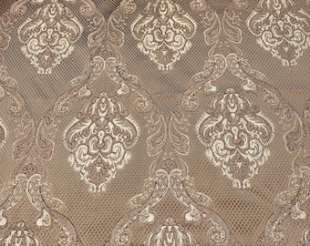 May include: A close-up of a brown fabric with a white damask pattern. The fabric has a subtle sheen and a textured surface.