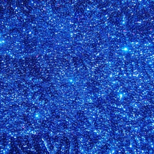 May include: A close-up of a blue fabric covered in sequins. The sequins are small and densely packed, creating a shimmering effect.