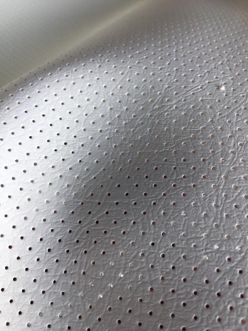 K&ouml;nnte beinhalten: Ein wei&szlig;es Material mit einer strukturierten, lederartigen Oberfl&auml;che, das ein gleichm&auml;&szlig;iges Muster aus kleinen, gleichm&auml;&szlig;ig verteilten kreisf&ouml;rmigen Perforationen aufweist. Das Material wird von oben links beleuchtet, was einen sanften Schattenverlauf erzeugt.