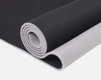 May include: Rolled-up yoga mat with a black textured top layer and a light gray, smooth underside. The mat is partially unrolled, revealing the contrasting colors and textures. Ideal for yoga and fitness.