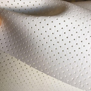 May include: White perforated fabric with a smooth texture. The fabric is folded in half, showing the underside of the material.