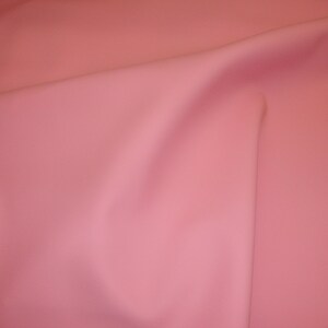 Puede incluir: Una tela lisa de color rosa p&aacute;lido con un pliegue sutil en el centro.
