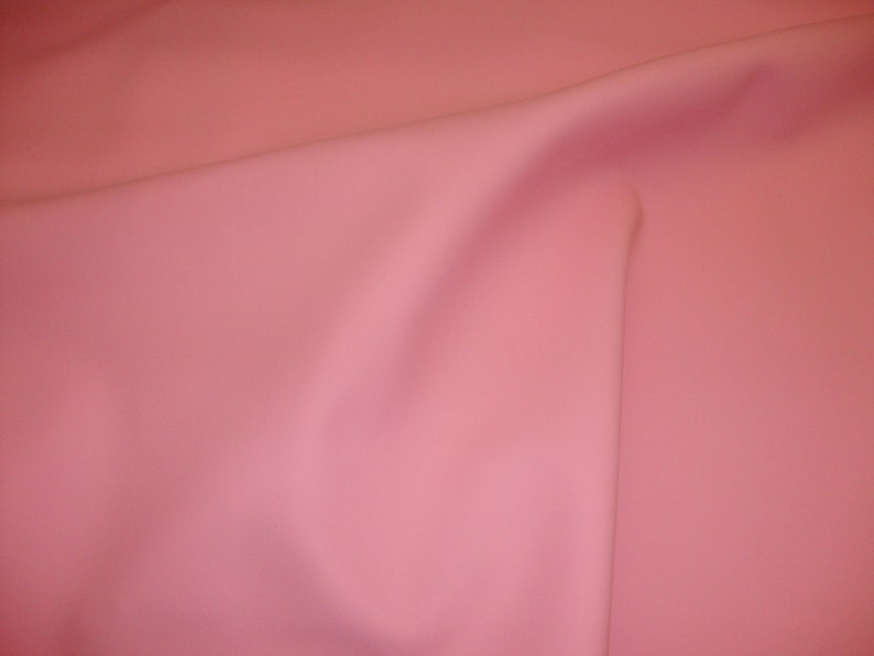Puede incluir: Una tela lisa de color rosa p&aacute;lido con un pliegue sutil en el centro.