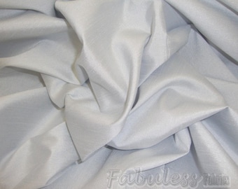 May include: A close-up of a smooth, light gray fabric with a subtle sheen. The fabric is draped and folded, showcasing its texture and drape.