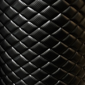 May include: Black quilted fabric with a diamond pattern. The fabric has a textured surface.