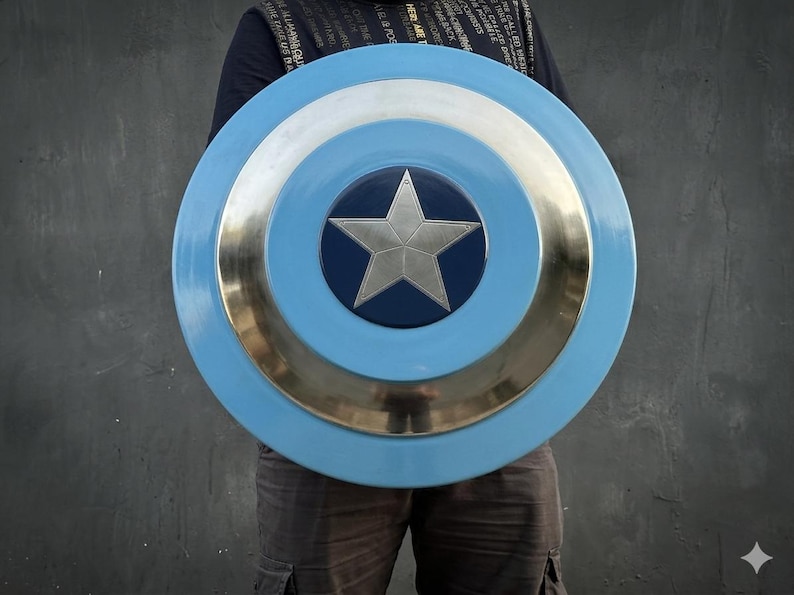May include: A circular shield in light blue, silver, and dark blue. The shield has a silver star at its centre, encircled by silver and light blue rings. The shield is held in front of a person.
