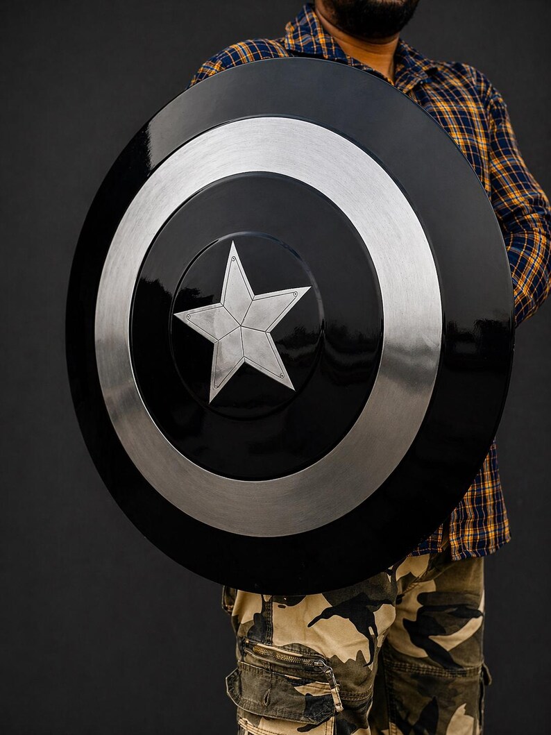 Puede incluir: Un escudo negro y plateado con un dise&ntilde;o de estrella plateada en el centro. El escudo tiene forma circular con un anillo plateado alrededor del borde. Es un accesorio o art&iacute;culo de colecci&oacute;n.