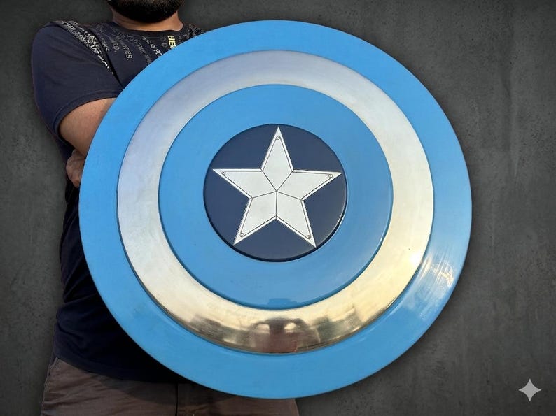 May include: A Captain America shield in blue, silver, and white. The shield has a series of concentric circles with a white star at the centre. This is a prop or collectible item.