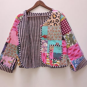 May include: A reversible quilted jacket featuring a patchwork design on one side with various colorful patterns including leopard print, floral motifs, and tropical fruit, and a black and white vertical striped pattern on the other side.